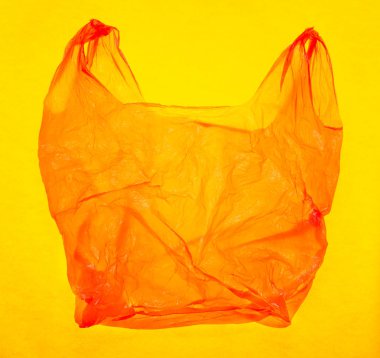 Sarı arka plan üzerinde parlak kırmızı plastik torba.
