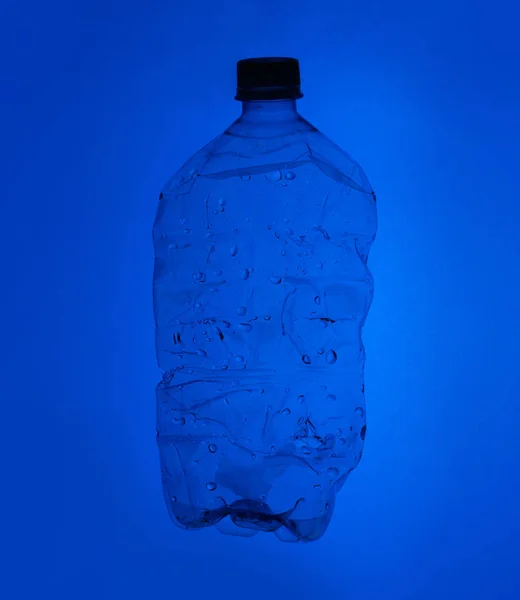 A large clear bottle on a white background. Bottle with blue lid. Plastic waste. Environmental problem.