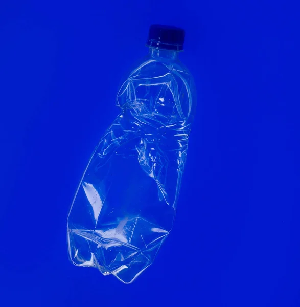 A large clear bottle on a blue background. Bottle with blue lid. Plastic waste. Environmental problem.