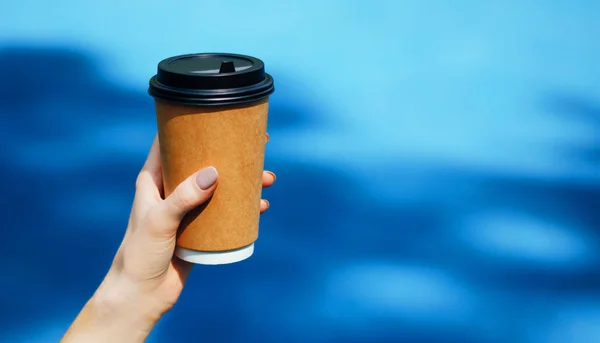 Coffee in hand. Blue background. A bright, attractive picture.