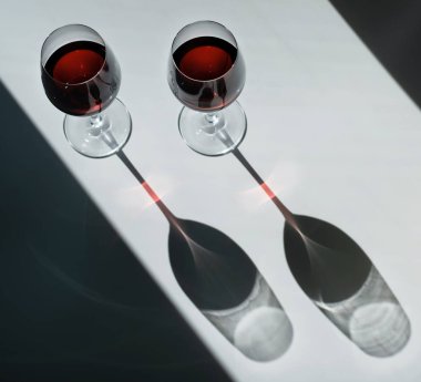 Sade bir arka planda parlak ışıkla iki kadeh kırmızı şarap. Üst görünüm.