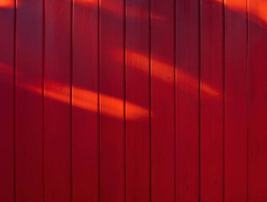 Kırmızı ahşap arka plan. Parlak bir arka plan. Ahşap doku. Dikey tahtalar. Arka planda güneş parlıyor.