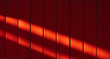 Kırmızı ahşap arka plan. Parlak bir arka plan. Ahşap doku. Dikey tahtalar. Arka planda güneş parlıyor.