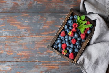 Yaz hala hayattır. Ahşap bir kutuda yabanmersini ve ahududu. Ahşap bir masada kompozisyon.