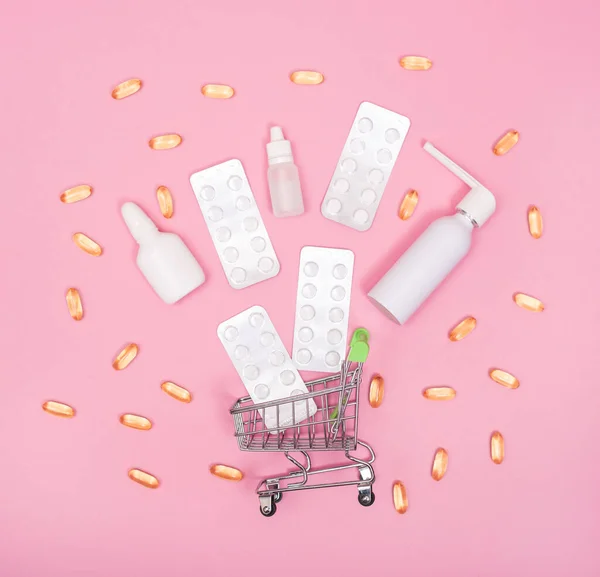 Shopping cart with various medicines. Pink background.