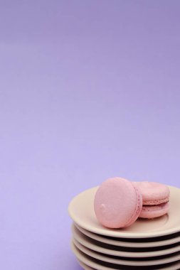 İki yavaşça pembe macaroons altı bej daire üzerinde. Kompozisyon bir lavanta arka plan üzerine yerleştirilen.