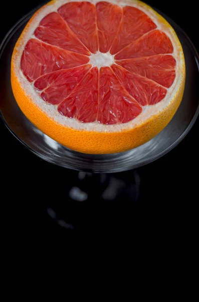 Grapefruit in a martini glass on a black background.