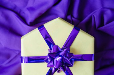 Mor bir yay ile sarı hediye kutusu.