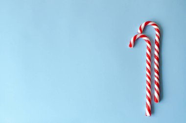 Beyaz ve mavi bir arka plan üzerinde kırmızı iki baston şekerler. Yeni yılın tarzı.