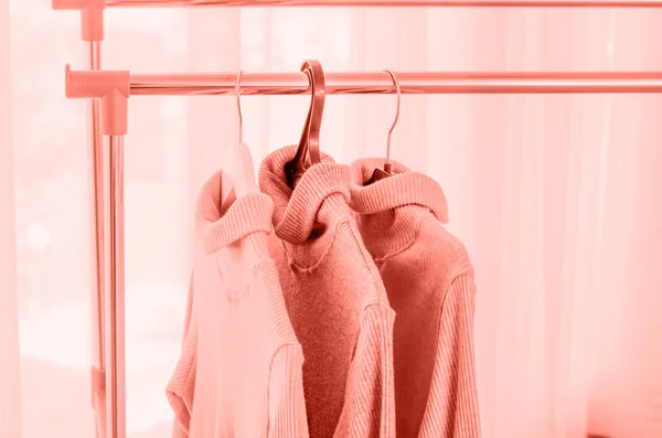Drei Pullover in Pastelltönen auf Kleiderbügeln. — Stockfoto
