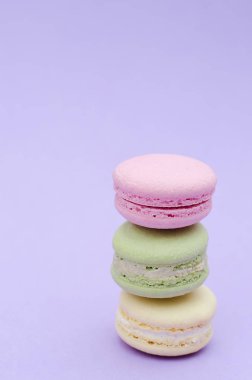 Üç acıbadem kurabiyesi sarı, yeşil ve pembe mor bir arka plan üzerinde.