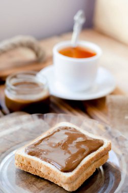 Fıstık ezmesi ile tost, çay bir kaşık ve bir kavanoz fıstık ezmesi.