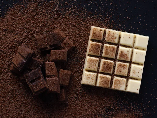 Different beautiful chocolate on a black background. Namely, it is milk chocolate, black and white.