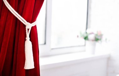 Bir büyük ve hafif pencere yakınındaki bir dekoratif dantel tarafından toplanan Bordo perde.