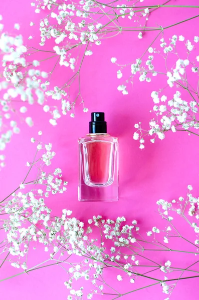 Parfüm pembe bir arka plan üzerinde bir kavanoz ile canlı gypsophila birçok twigs.