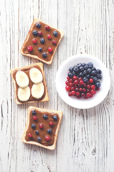 Drie Toast Met Pindakaas Bessen Bananen Een Schotel Van Bessen — Stockfoto