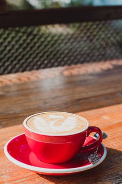 Kırmızı fincan kapuçino. Bir tablodur. Kapuçino güzel krematoryum ve desen.