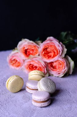 Bademli kurabiye bir deste ile gri beton zemin üzerine güzel şeftali renkli gül buketi.