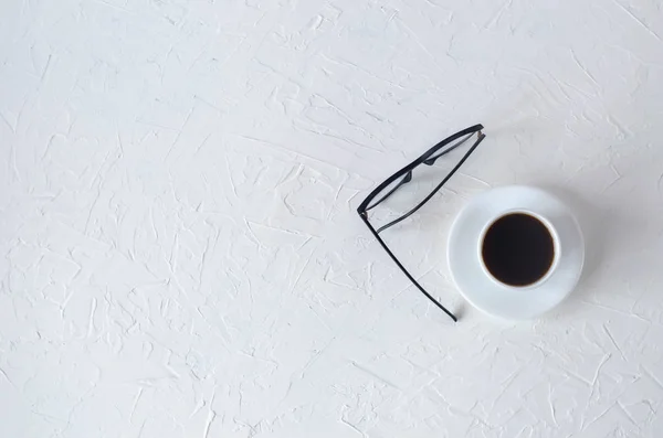 Una taza de café con un platillo y vasos sobre un fondo blanco . —  Fotos de Stock
