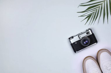 Flatley gri arka plan spor ayakkabıları, kamera ve palmiye dalı.