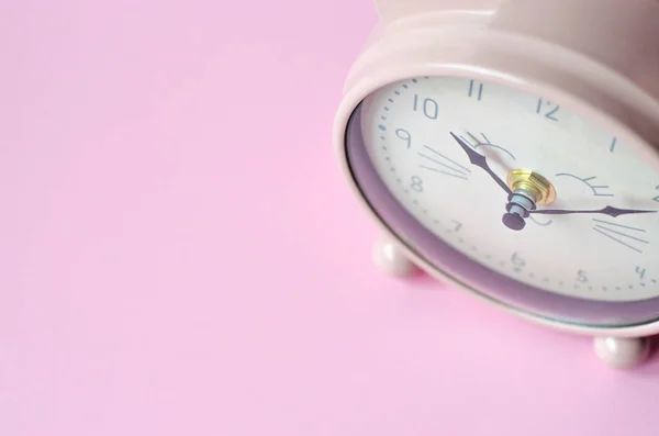 Pink alarm clock in the form of a cat on a pink background.