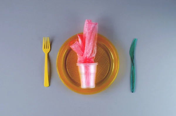 Plastic utensils and plastic bag on a gray background — Stock Photo, Image