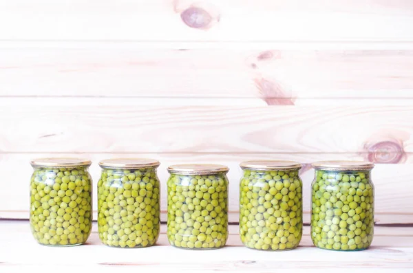 Varias latas de guisantes enlatados sobre un fondo de madera . — Foto de Stock