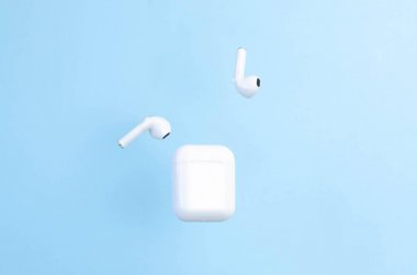 Mavi arka planda kılıflı kablosuz beyaz kulaklıklar.