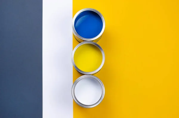 Três latas de tinta multicolorida em um cinza-laranja com um fundo branco . — Fotografia de Stock