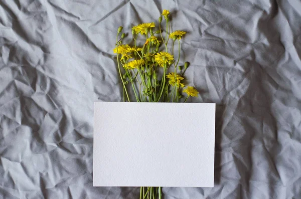 White sheet on a gray fabric background with yellow flowers.