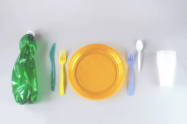 Plastic utensils and plastic bag on a gray background. — Stock Photo, Image