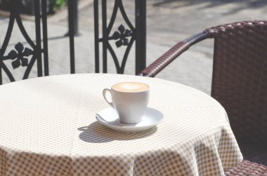 Damalı masa örtüsü ile masada bir fincan kahve. 