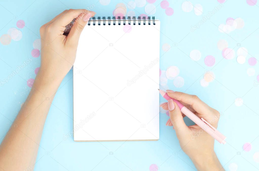 Female hands write something in a notebook.