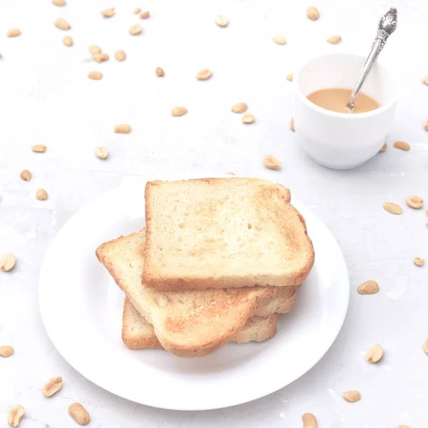 Een stapel toast met pindakaas en pinda's rond op de tafel. — Stockfoto