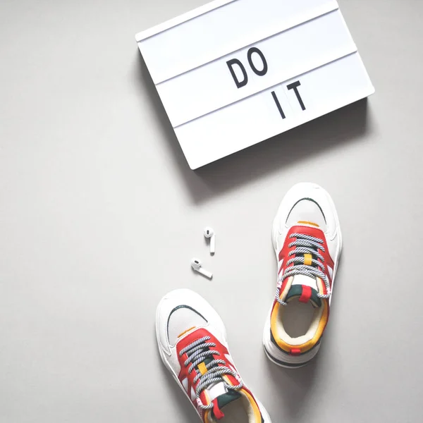 Scarpe da ginnastica, cuffie e un cartello con scritto fallo . — Foto Stock
