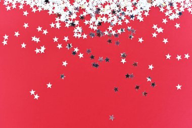 Kırmızı arka planda gümüş yıldızlı konfeti. 