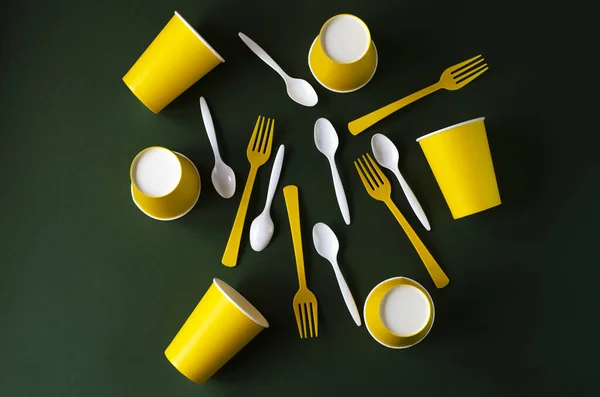 Flat lay plastic and paper utensils on a green background. — Stock Photo, Image