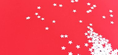 Kırmızı arka planda gümüş yıldızlı konfeti. 