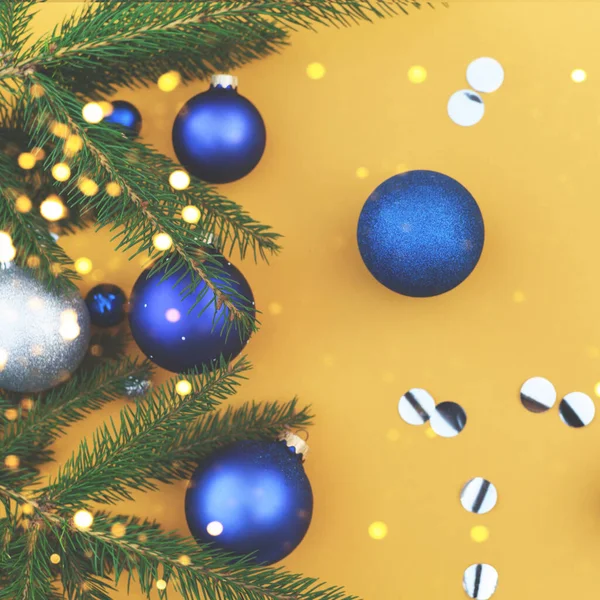 Ramo de árvore de Natal decorado com brinquedos azuis em um fundo laranja . — Fotografia de Stock