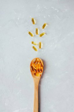 Kapsüllerdeki balık yağı gri arka planda tahta bir kaşıkta. Halk tıbbı. Alrerntiva tıbbi hazırlıklar. Virüs enfeksiyonunun önlenmesi.