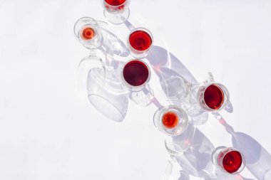 Beyaz arka planda farklı türde bardaklarda şarap. Gözlükten yapılmış şık sert gölgeler.