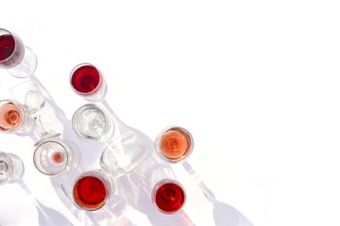 Beyaz arka planda farklı türde bardaklarda şarap. Gözlükten yapılmış şık sert gölgeler.