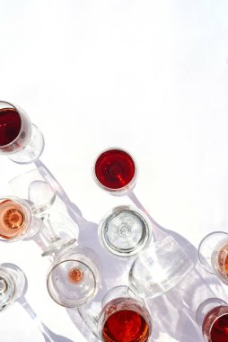 Beyaz arka planda kırmızı, beyaz ve gül şarabı olan bardaklar. Dikey fotoğraf.