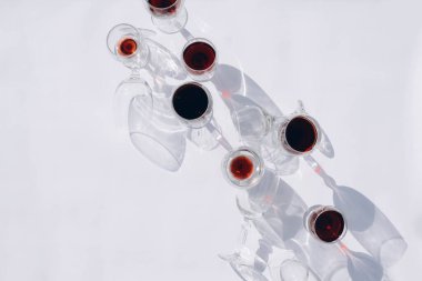 Beyaz arka planda farklı türde bardaklarda şarap. Gözlükten yapılmış şık sert gölgeler.