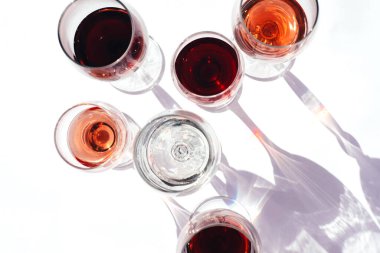 Beyaz arka planda kırmızı, beyaz ve gül şarabı olan bardaklar. Yatay fotoğraf.