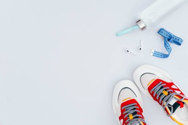 Açık gri zemin üzerinde spor düz yatıyordu. Spor aksesuarları: spor ayakkabıları, su ve kulaklıklar. Çevrim içi eğitim.