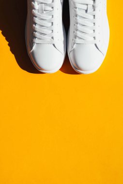 Turuncu arka planda sert gölgeli beyaz spor ayakkabılar. Şık spor ayakkabıları..