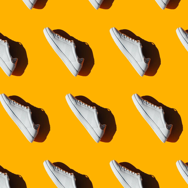 A pattern of white sneakers on an orange background. Shoes pattern.