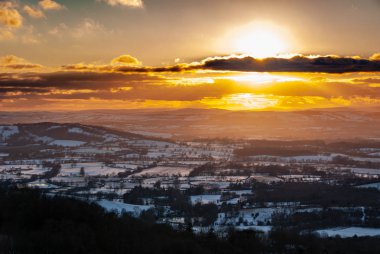 Cotswolds içinde İngiliz kış kar altında altın bir günbatımı blanketed