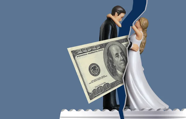 To illustrate how money issues can come between couples and cause divorce, a one hundred dollar bill comes between a bride and groom wedding cake topper. This is a photo-illustration.